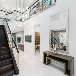 SLEEK CONTEMPORARY METALLIC RESIDENCE metal credenza, coved mirror, glass staircase, gallery wall, white walls, loft, open concept