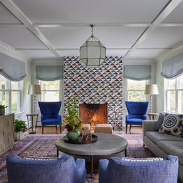 Kenilworth Living Room. Coffered ceiling with eclectic tile fireplace, blue accents, classic oriental rug & modern media cabinet.