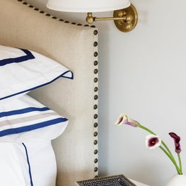 Brass swing arm sconces, navy bedding. modern bedroom