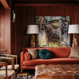 Craftsman library with bold artwork, burnt orange sofa, leather ottoman, florals