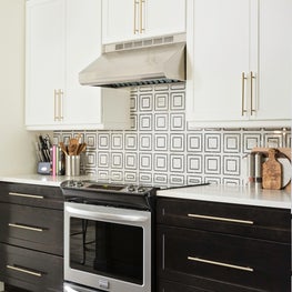 Contrasting black & white cabinets, polished brass handle & geometric backsplash