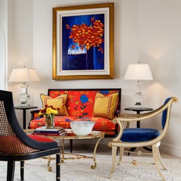 This formal sitting area has a bright floral patterned sofa & a royal blue chair