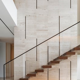 Custom design staircase in walnut, open pore vein cut travertine bronze strips