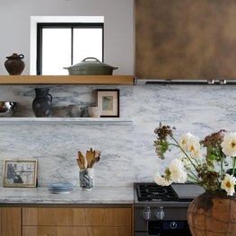 Kitchen with Stone Backsplash and Brass Hood