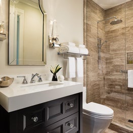 This bath features a faux-wood ceramic tiled shower with dark wood vanity.