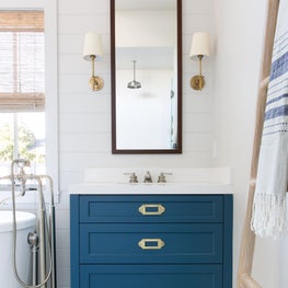 Modern farmhouse master bathroom with blue vanity, tile floor and shiplap walls.