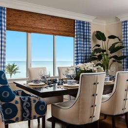 This dining room has ocean views that are framed by large gingham draperies.