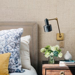 Master bedroom with upholstered headboard, wall sconces, grasscloth wallpaper.