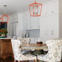 Glenview Kitchen. White and blue kitchen with wood island, antique breakfast table, upholstered chairs & red pendants.