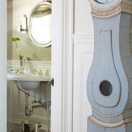 A Gustavian clock sits outside the powder room. 