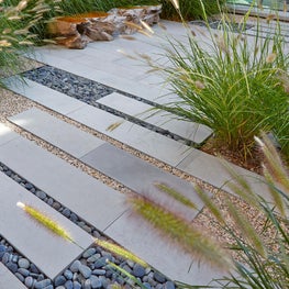 The front entrance layered with pavers, gravel bands, and Pennisetum grasses.