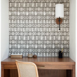 Built-in home office with black and white ethnic wallpaper and white cabinets