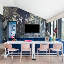 Portfolio: A TV room with dusty pink stacking chairs, white tables, a Phillip Jeffries wall covering and view of the coastline.