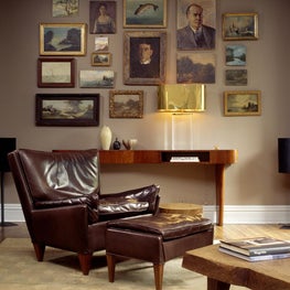 A gallery wall above an Italian mahogany console table & lucite brass lamp 