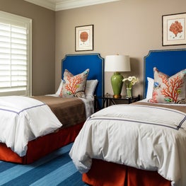 Marine style guest bedroom with blue striped rug, beige walls, and sealife motif