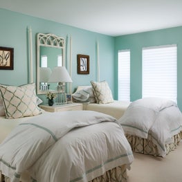 This serene guest bedroom has Tiffany blue walls and light ivory case-goods.