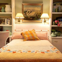 Period guest room with vintage linens and custom headboard