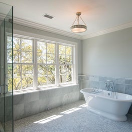 Carrara Marble Bathroom with Windows, Tile Wainscoting and Freestanding Tub