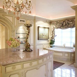 Awash in tones of cream and rose, the room is topped with a ceiling of blush-colored Venetian plaster and decked with a gleaming floor of inlaid rose quartz circles.  