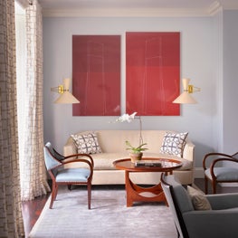 Sun soaked seating in a NYC apartment living room with a pop of color 