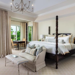 This elegant master suite features Cowtan & Tout neutral fabrics and a chandelier by Visual Comfort.