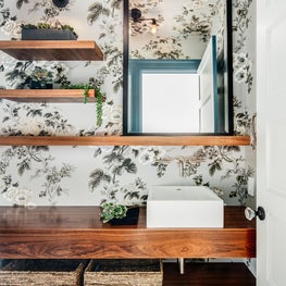 Bathroom with floral wallpaper, geometric floor tiles, and floating wood vanity.