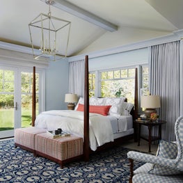 Lake Geneva Bedroom. Four poster bed on navy oriental rug with blue checked settee & lantern lighting.