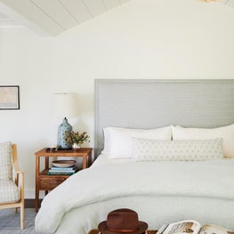 Blue and white master bedroom with upholstered headboard and rattan ceiling fixture