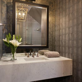 Metallic neutral wallcovering with assorted metal finishes in this updated powder room.