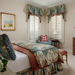 This colorful guest room is abundant in natural light through the white shutters