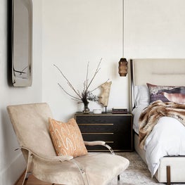 Portfolio: Warm and cozy primary bedroom with plaster walls, hanging pendant lights, and a gold mirror