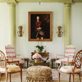 An oil painting framed in gold and flanked by candelabra sconces.