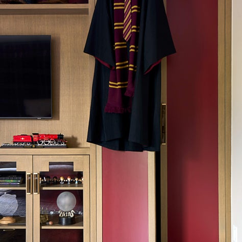 Laura U Design Collective, cover: Custom millwork displays Harry Potter memorabilia and provides concealed storage, while rich burgundy accents capture the theme elegantly.