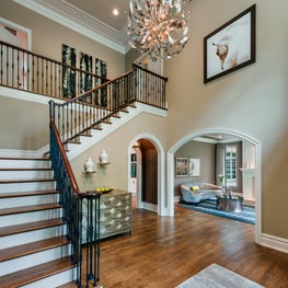 Dramatic chandelier and artwork add drama to this double height foyer from Viola