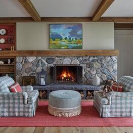 Three Barn Farm Great Room. Sitting area with stone fireplace & red accents.