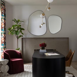 Portfolio: A sculptural black desk, asymmetrical mirrors, and layered lighting create a workspace with bold contemporary character.