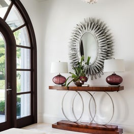 The dramatic arched entry is echoed by a hand carved oval framed mirror.