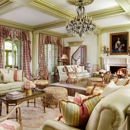 A grand room with plush seating, chandelier, and elegant window treatments.