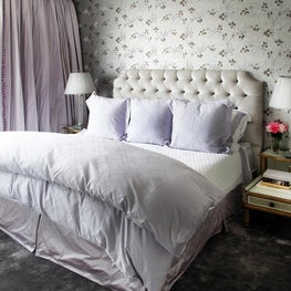 Traditional master bedroom with floral wallpaper, tufted headboard