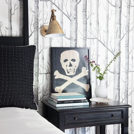 Bedside Detail. Skull and Crossbones Art. Mural Wallpaper. Aged Brass Sconce.