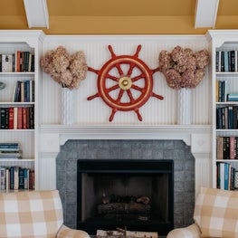 Glenview Family Room. Teal, tan and red scheme with white fireplace cabinetry, beamed ceiling & large chandelier.