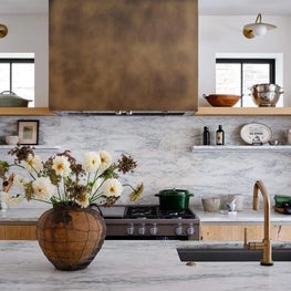 Kitchen with Stone Backsplash and Brass Hood