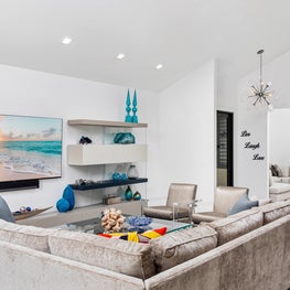 LAKEFRONT CONTEMPORARY VILLA, modern den, neutral den, beige sectional, floating shelves, blue art glass