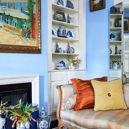 Salon detail of a historic home with built in bookcases filled with blue and white export and decorated with antiques.