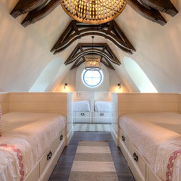 Girls Bunk Room with Round Window under Vaulted Ceiling and Dark Wood Brackets