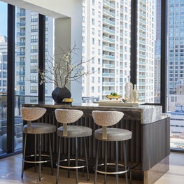 A custom bar inspired by Joseph Dirand combines fluted wedge wood, Orobico marble and antique brass base.