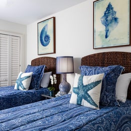 This guest room is a symphony of cool blues contrasting  the rattan headboards.