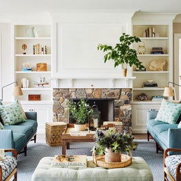 Blue and white coastal living room with stone fireplace and patterned textiles