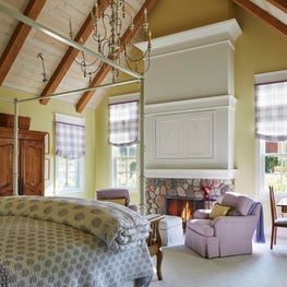 Three Barn Farm Bedroom. Yellow and purple scheme with vaulted wood beam ceiling & canopy bed.