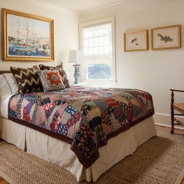 This traditional guest bedroom is adorned by a colorful patchwork coverlet.